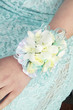woman's hand on blue dress with white flower corsage on wrist