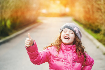 Wall Mural - Laughing girl showing thumbs up.