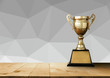 golden trophy on wood table with gray White Polygonal Mosaic Bac