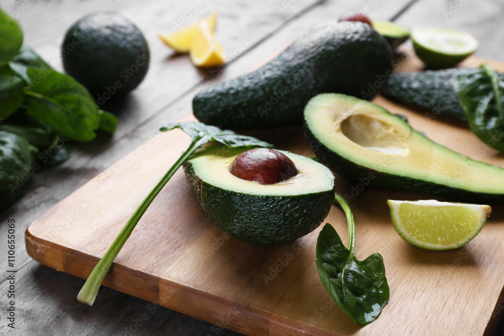 Sliced avocado with lime and spinach on wooden cutting board