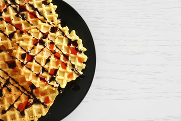 Wall Mural - Plate of waffles with chocolate glaze on wooden background