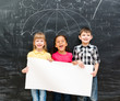 © Ievgen Skrypko - three cheerful children holding white empty paper sheet with drawn umbrella on blackboard on the background