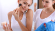 © shefkate - Beautiful girls looking in the mirror and applying cosmetic with a big brush