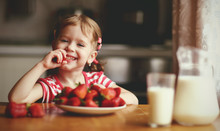 Happy Child Girl Eats Strawberries In Summer Home Kitchen