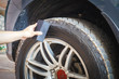 Man's hand holding a blue fabric cleaning car tires and wheels