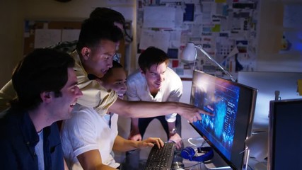  Young creative computer design team working together in dark office.
