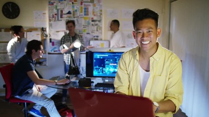  Portrait of smiling young computer programmer working in office with others