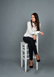 © Khrystyna Bohush - Beautiful young brunette girl sitting on a white chair. Pretty woman in white blouse