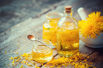 Wall Mural - Dandelion tincture or oil bottles, mortar and honey on table. He