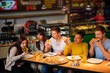 © Nejron Photo - Cheerful multiracial friends having fun eating pizza in pizzeria.