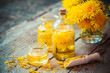 Bottles of dandelion tincture or oil, flower bunch, wooden scoop