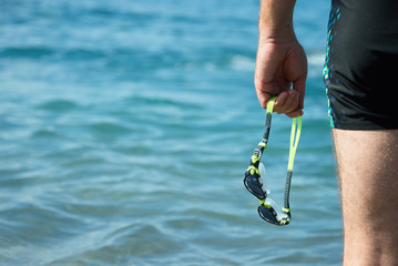 Swimmer with swimming goggles in hand at the entrance to the sea