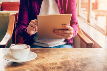 Woman hands using and holding  computer tablet in coffee shop wi