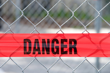 Red reflective danger barrier tape across a chain link fence