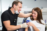 Fototapeta  - Dentist handing cup of water to a patient after treatment