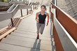 © Connect Images - Female runner running up urban stairway