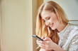 © Connect Images - Young woman reading smartphone text at home