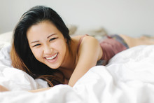 Portrait Of Young Woman, Wearing Underwear, Lying On Bed, Laughing