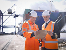 Ship's Captain Discussing Loading Cargo With Port Worker