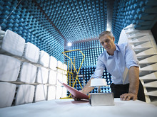Scientist Preparing To Measure Electromagnetic Waves In Anechoic Chamber, Low Angle View