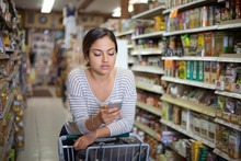 Young Woman Shopping With Smartphone In Health Food Store