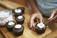 Womans Hands Icing Cup Cakes On Chopping Board