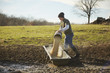 © Connect Images - Mature male farmer pouring grain into feeding trough in field