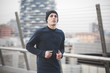© Connect Images - Young male runner running on city footbridge