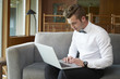© Connect Images - Portrait of man sitting on sofa working from laptop