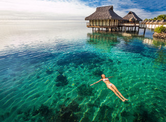 Wall Mural - Woman in white bikini swimming in coral lagoon, Moorea, Tahiti