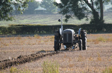 A Vintage Tractor Ploughing A Farmers Field.