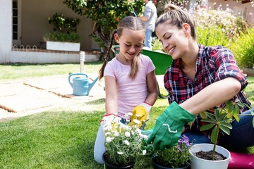 Wall Mural - Smiling mother and daughter gardening together in garden