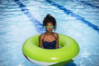 © Connect Images - Girl standing in inflatable ring in swimming pool, wearing goggles looking at camera