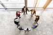 © Connect Images - Overhead view of businessmen and women in circle holding hands