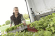 Smiling woman farmer putting trays in truck