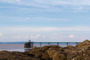 View over rocks at Clevedon sea front, including pier in backgro