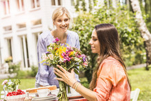 Two Female Friends In Garden, Looking At Bunch Of Flowers