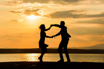 Wall Mural - A couple dancing salsa by the sea at sunset