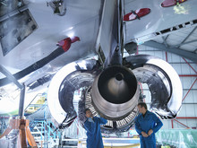 Engineers Working On Jet Engine In Aircraft Maintenance Factory
