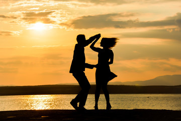 Wall Mural - Couple silhouette dancing by the sea at sunset