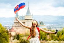 Young Female Tourist Having Fun Traveling With Slovak Flag At Bojnice Castle In Slovakia. Promoting Tourism In Slovakia