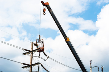 technician works in a bucket high up on a power pole