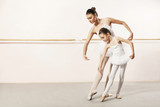 Fototapeta  - Little ballerina dancing with ballet teacher in dance studio