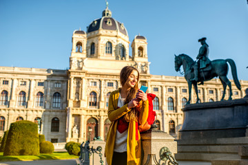 Wall Mural - Young female tourist with smart phone on Maria Theresa square near museum of Natural history in Vienna.