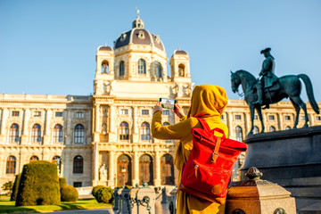 Wall Mural - Young female tourist photographing with smart phone museum of Natural history in Vienna.