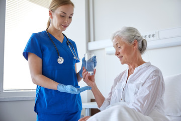 nurse giving medicine to senior woman at hospital