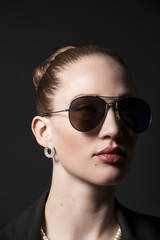  Portrait of Beautiful young woman in sunglasses on black backgro