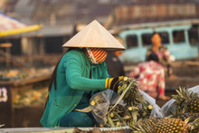 Vietnamese Woman With Typical Conical Hat ( Sugegasa),  Cut Pineapple Fruits In The  Cai Rang Floating Market On The Mekong Delta. Can Tho, Vietnam