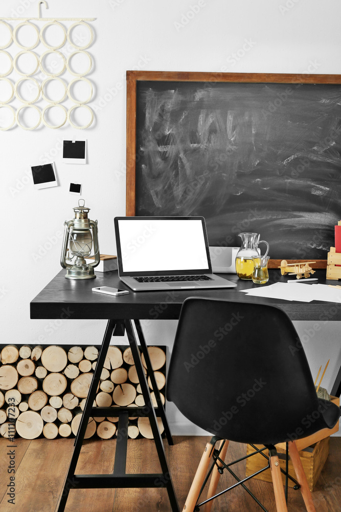 Desktop with notebook and other items on blackboard background