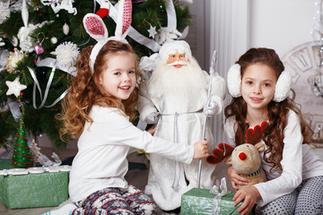 Little girls in comfortable home clothes sitting on floor in bea